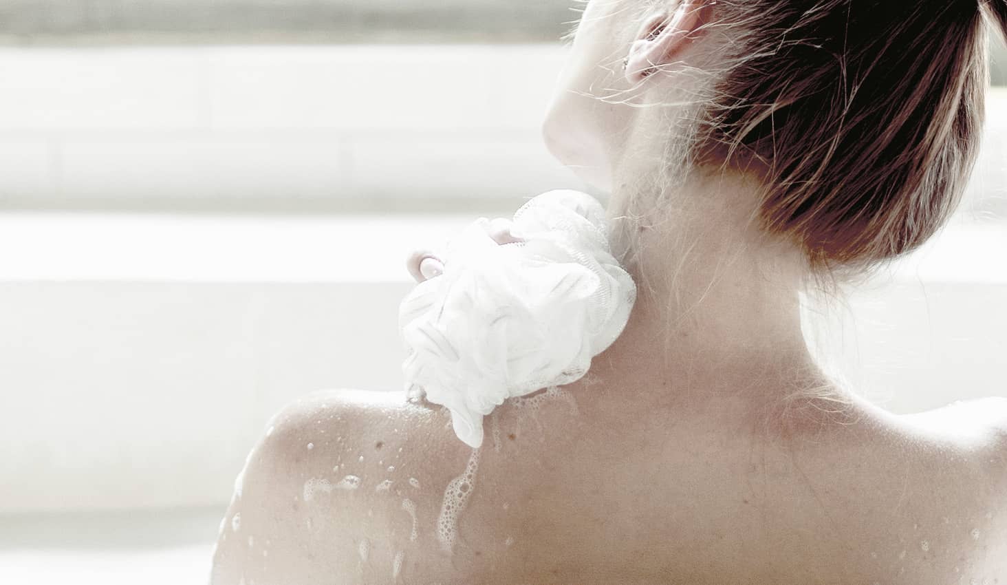 Mujer tomando un baño con un estropajo